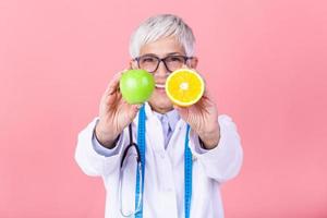 content diététicien nutritionniste en portant Pomme et Orange ayant amusement. femme promouvoir en bonne santé nourriture fruit. droite en mangeant nutrition et minceur concept. photo