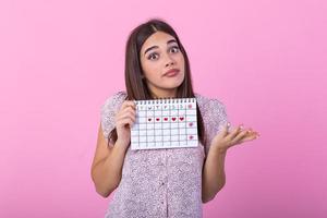 portrait de Jeune femme dans robe, en portant femelle périodes calendrier pour vérification menstruation journées isolé sur tendance rose Contexte. médical soins de santé, gynécologique concept. photo