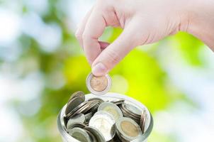 femme main en mettant une pièce de monnaie sur vert la nature arrière-plan, enregistrement ,don investissement fonds financier soutien charité dividende marché croissance photo