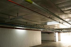 tuyaux de système sanitaire et câbles électriques installés sous une structure en béton armé de dalles plates dans le bâtiment.tuyaux de ventilation dans un parking souterrain photo