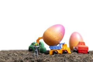 Les gens miniatures travaillant sur les oeufs de Pâques pour le jour de Pâques avec un fond blanc photo