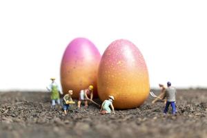 Les gens miniatures travaillant sur les oeufs de Pâques pour le jour de Pâques avec un fond blanc photo