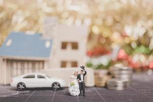 mariée et le marié miniature avec des pièces devant une maison, concept de famille réussie photo