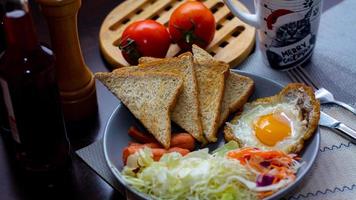 petit-déjeuner, frit œufs, frit saucisse, légume salade et pain grillé sur une marron en bois table avec café. photo