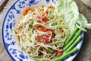 somme toute, thaïlandais épicé Papaye salade sur blanc arrière-plan, international thaïlandais nourriture connu et populaire, fabriqué avec Papaye et tomates, il goûts aigre, sucré et épicé. photo