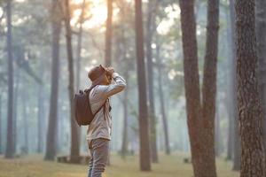 oiseau observateur est à la recherche par jumelles tandis que explorant dans le pin forêt pour arpentage et découvrir le rare biologique la diversité et écologiste sur le champ étude concept photo