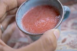 proche en haut photo de Frais fraise jus sur le bleu tasse à le jardin magasin. le photo est adapté à utilisation pour en bonne santé boire, menu arrière-plan, et boisson contenu médias.