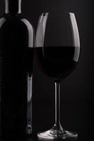 Bouteille de vin gros plan et verre avec fond noir photo