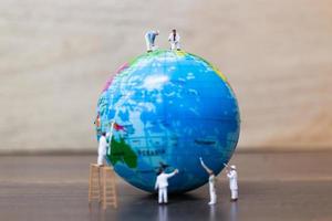 Peintres miniatures peinture sur un globe avec un fond en bois, sauvez le concept de la terre photo