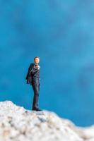 homme d & # 39; affaires miniature debout sur un rocher avec un fond bleu photo