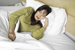 une triste Jeune asiatique femme est pleurs tandis que mensonge sur le lit photo