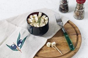 Feta marinée sur une assiette sur une planche de bois avec des épices sur fond blanc photo