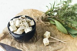 Feta marinée sur une assiette sur une planche de bois avec des épices sur fond blanc photo