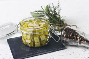 Feta marinée dans un bocal en verre et épices sur un fond blanc photo