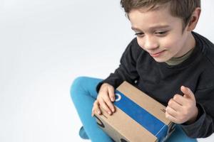 le enfant détient une papier carton boîte avec une cadeau expédié par le livraison service. photo