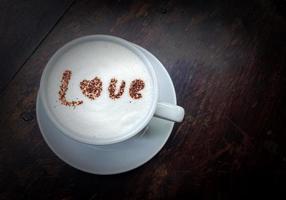 chaud Frais Lait dans une blanc tasse surmonté avec Lait mousse et saupoudré avec Chocolat dans le des lettres amour.doux et sélectif se concentrer. photo