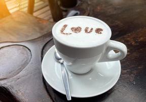 chaud Frais Lait dans une blanc tasse surmonté avec Lait mousse et saupoudré avec Chocolat dans le des lettres amour.doux et sélectif se concentrer. photo