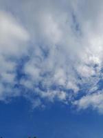 nuages blancs dans le ciel bleu. beau fond bleu clair. peu nuageux, beau temps. nuages bouclés par une journée ensoleillée. photo