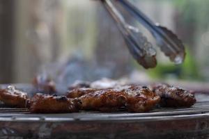 grillé poulet ailes sur le gril avec fumée allumé flottant sur le ancien poêle. photo