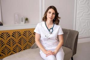 mignonne fille médecin séance à une table avec une stéthoscope photo