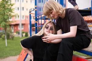 deux adolescent les filles sont séance sur le terrain de jeux avec une téléphone photo