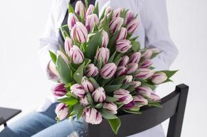 une grand bouquet de tulipes de différent couleurs dans le mains de une femme photo