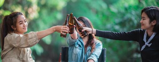 jeunes femmes assises et buvant des boissons en camping en forêt photo