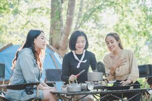 les jeunes femmes cuisinent et utilisent un smartphone pour prendre des photos en camping