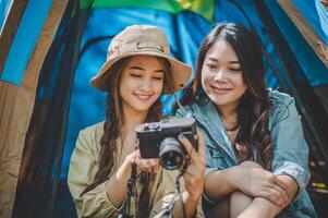 jeune femme utilise un appareil photo pour prendre une photo et montrer à ses amis