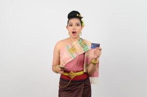 portrait de magnifique thaïlandais femme dans traditionnel Vêtements posant avec billet de banque et crédit carte photo