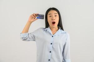 portrait d'une jeune femme asiatique positive montrant un salaire de bonne humeur par carte de crédit isolé sur fond blanc photo
