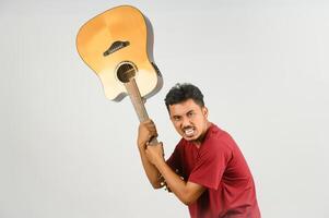 portrait de jeune homme asiatique en t-shirt rouge avec une guitare acoustique isolé sur fond blanc photo