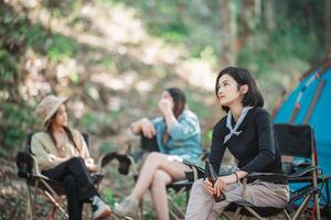 les jeunes femmes applaudissent et boivent une boisson devant la tente de camping photo