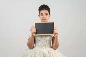 jeune belle mariée asiatique pose avec un tableau blanc à la main photo