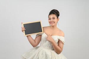 jeune belle mariée asiatique pose avec un tableau blanc à la main photo