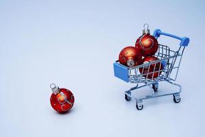 une Chariot de le supermarché, porter Noël des balles, Noël et Nouveau année sur une bleu Contexte. photo