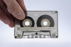 une homme main détient un vieux coloré verre transparent l'audio cassette pour une ruban enregistreur photo