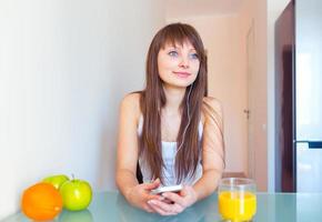 Jeune fille dans le cuisine écoute à la musique sur écouteurs photo