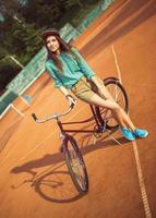 fille branché permanent avec magenta bicyclette sur le tennis tribunal photo