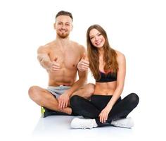 athlétique homme et femme après aptitude exercice avec une doigt en haut sur le blanc photo