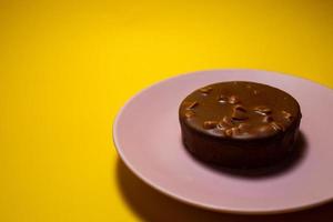 Chocolat tartelette avec salé caramel sur une rose plaque. Jaune arrière-plan, Haut vue photo