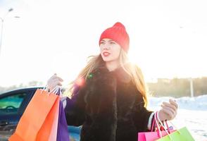 souriant caucasien femme en portant sa achats sac près le voiture photo