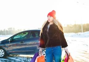 souriant caucasien femme en portant sa achats sac près le voiture photo