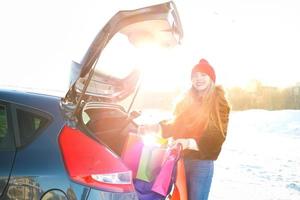 souriant caucasien femme en mettant sa achats Sacs dans le voiture tronc photo