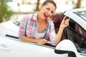 Jeune jolie femme est permanent près le convertible voiture avec le clés dans main photo