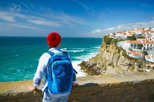 femme avec une sac à dos jouit une vue de le océan côte près azenhas faire mar, le Portugal photo