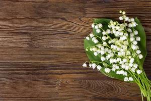 bouquet de fleurs de lys de le vallée sur le en bois Contexte photo