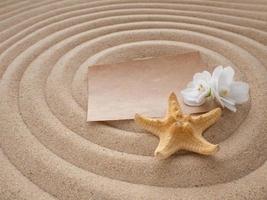 lettre dans le sable. papier avec fleur et étoile de mer sur le le sable dans le forme de une spirale. le concept de une plage vacances photo