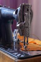 vieux rétro couture machine et Orange en tissu prêt pour couture. le presseur pied est abaissé. peu profond profondeur de champ. concentrer sur le presseur pied. vertical. photo