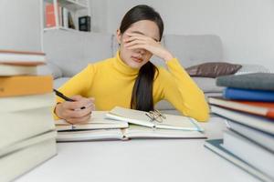 une étudiante asiatique a de l'anxiété à cause des examens, les femmes se préparent aux tests et apprennent les leçons à la bibliothèque. stress, désespoir, hâte, incompréhension lecture, découragement, attente, connaissance photo